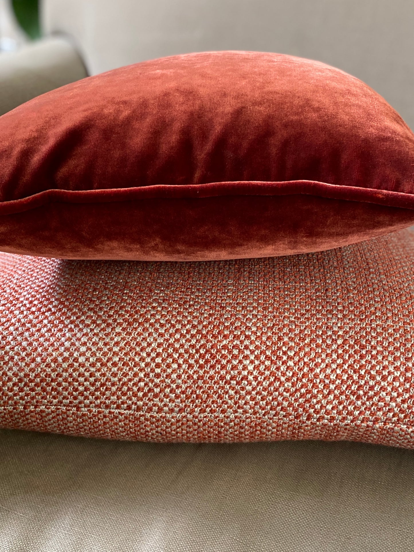 Two autumnal cushions . A chestnut velvet square cushion laid on top of a woven chestnut and cream cushion.