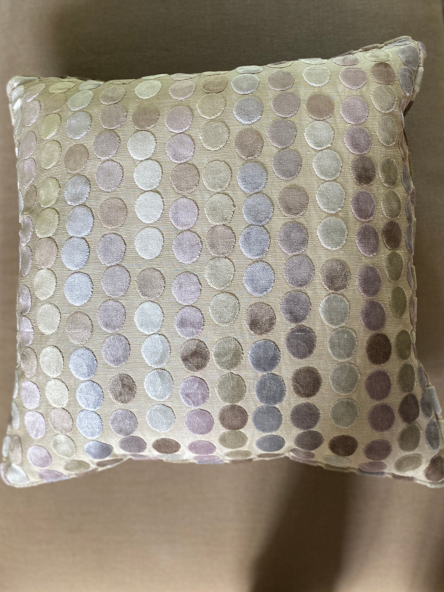 Overhead of cut pile velvet cushion showing pastel dots and beige background and piping around the edges.