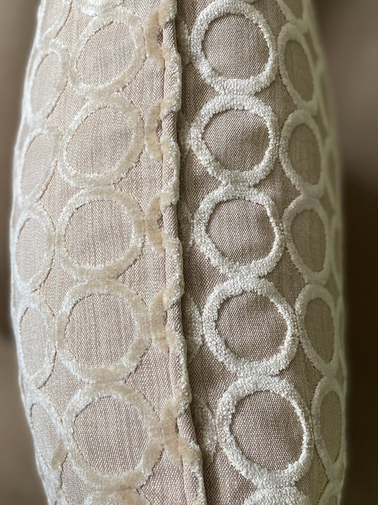 Close up of piping on taupe cushion with beige background and cut pile circle velvet design.