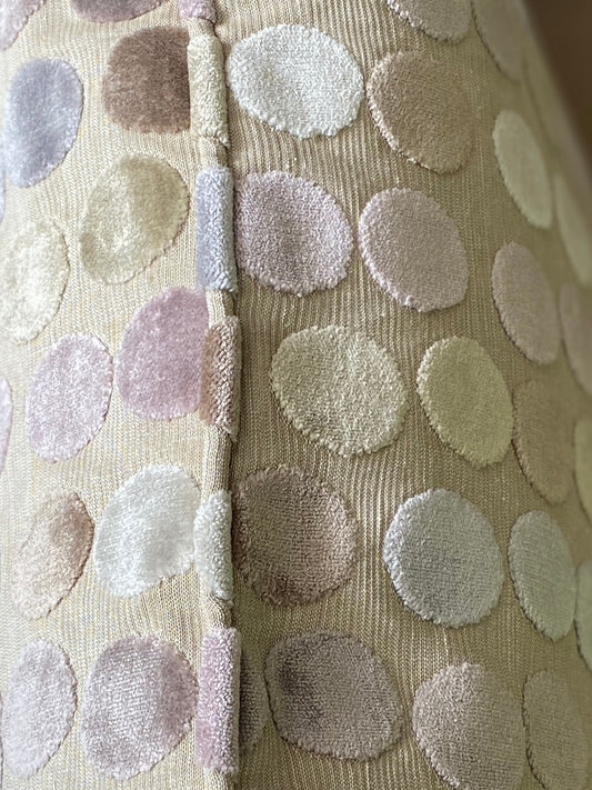 Close up of piping on a pastel dot cushion of cut pile velvet with a beige background.