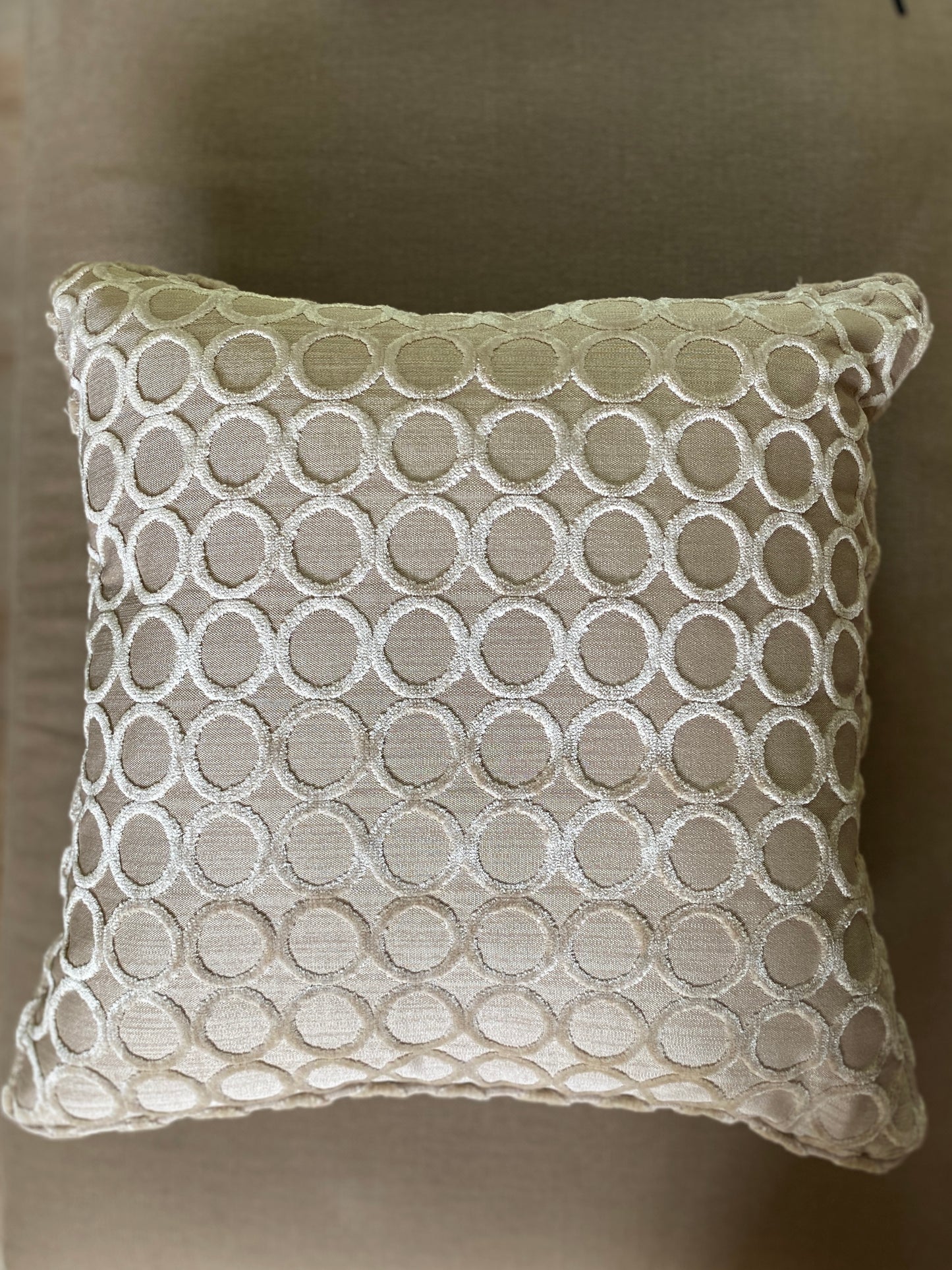 Over head of taupe cut pile velvet cushion with self piping and circle design. Has pale beige background and is square measuring 50 x 50cm