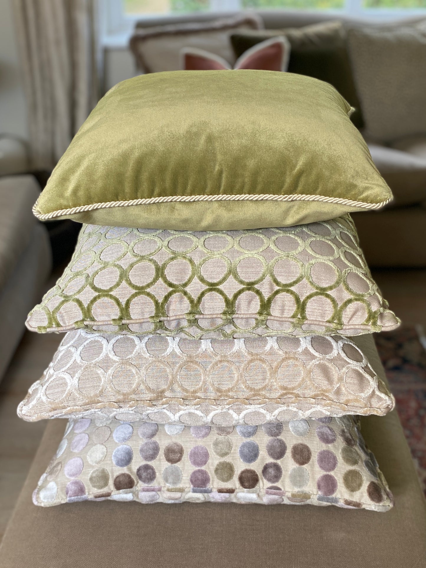 Pile of cushions. 3 with circle designs in cut velvet and neutral backgrounds and a moss green velvet cushion with cord trim