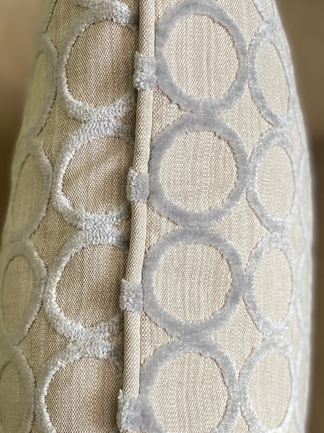 Close up of piping on silver grey cut pile velvet cushion with circle design.