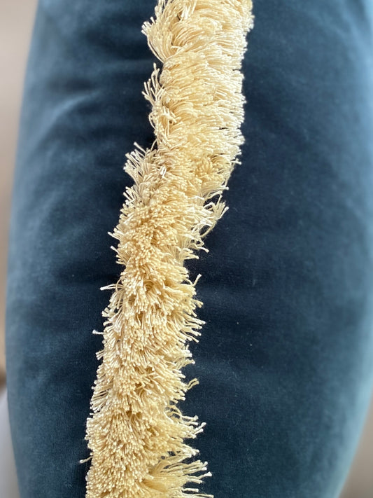 Close up of teal velvet cushion with complimentary natural fringing.
