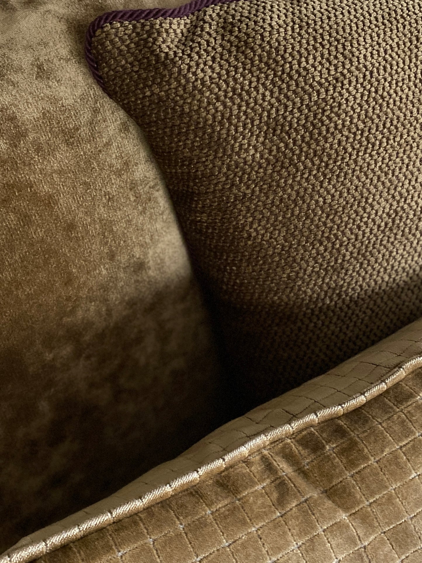An antique gold velvet cushion paired with two textured chenille cushions in burnished gold.