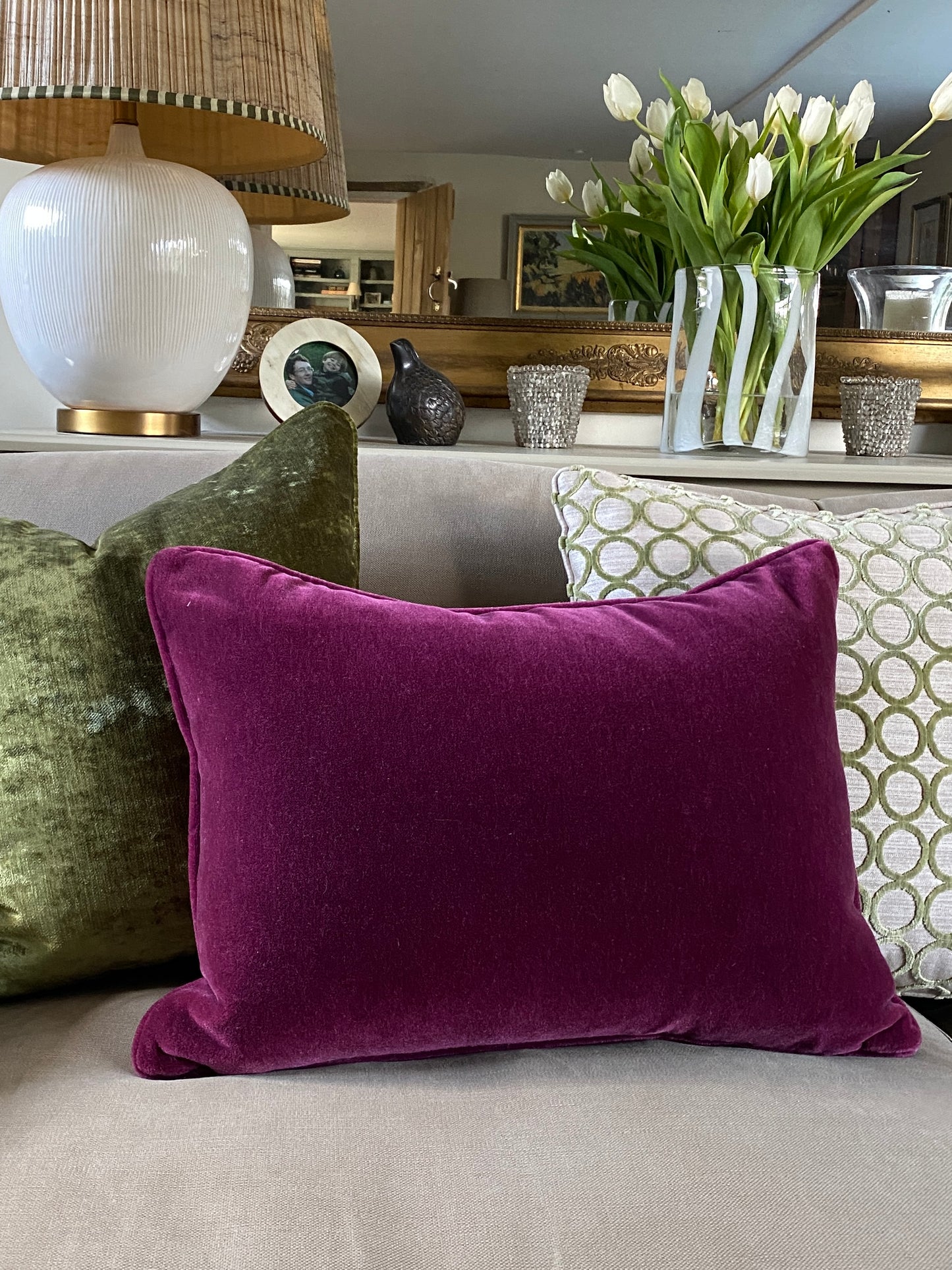 Raspberry mohair velvet cushion on a sofa with green cushions behind