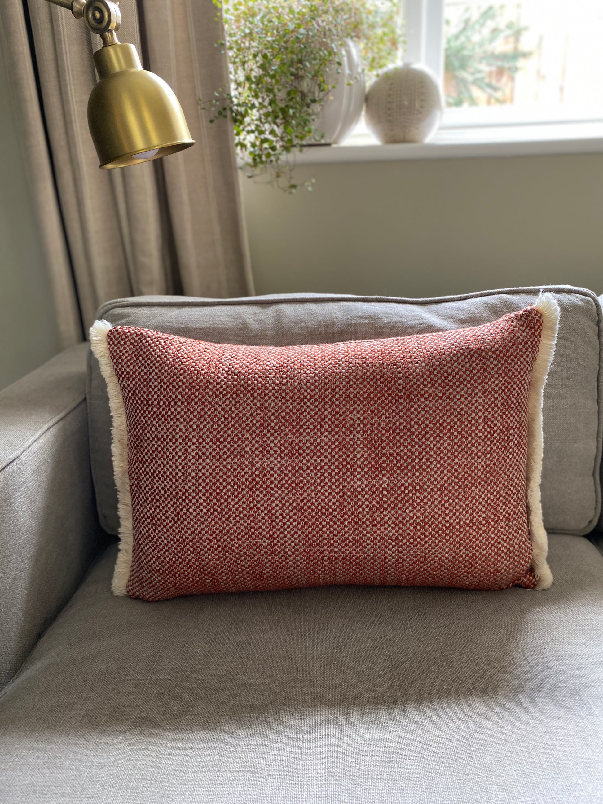 Autumnal chestnut and cream woven textured rectangular cushion with cream wool fringing at each end.