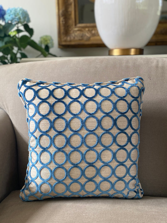 Square teal cut pile velvet cushion in a circle design with a beige background and self piping trim.