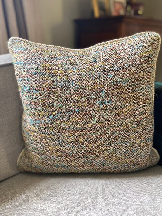 Herringbone wool and silk cushion with pops of colour in browns, green and blues on a sand coloured background with a natural cotton cord piping. 
