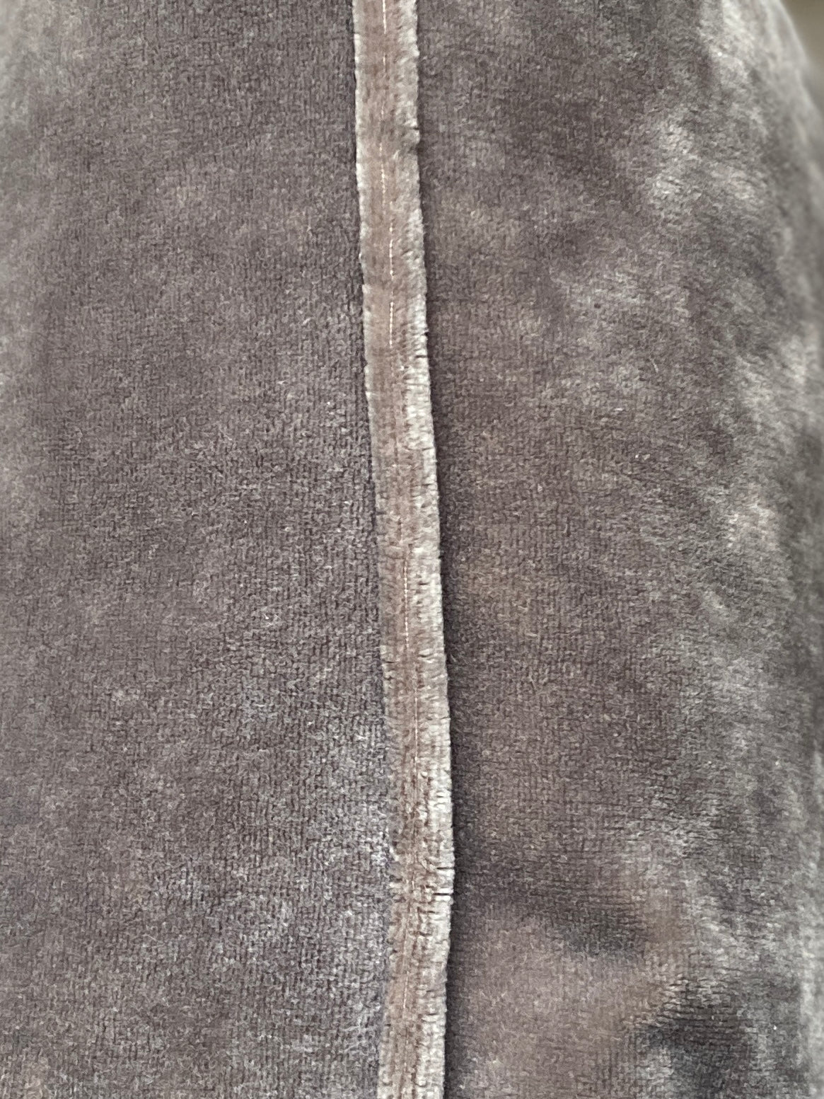 Close up of piped trim around grey velvet cushion