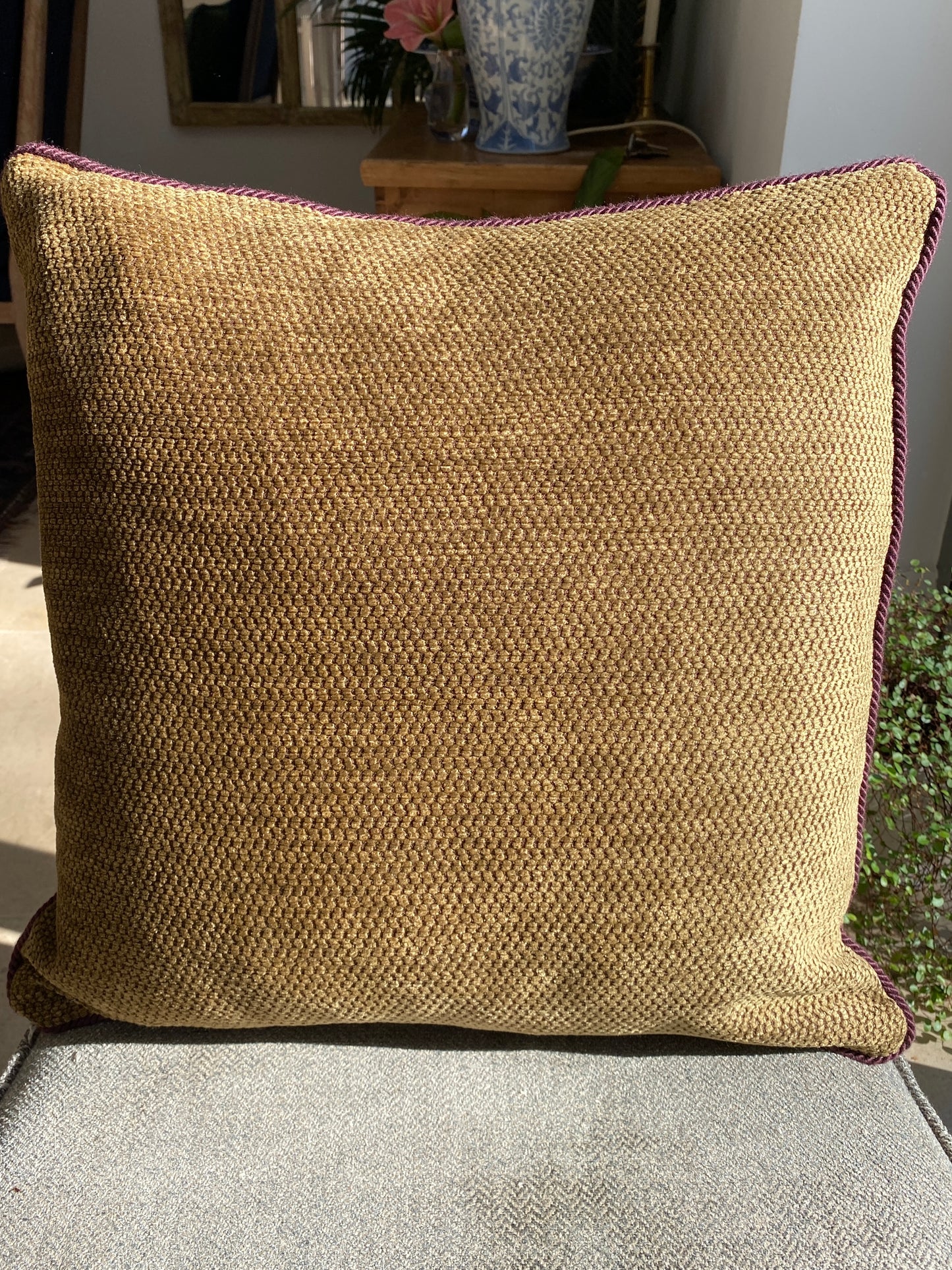 Textured burnished gold chenille cushion on a chair with a blurred background
