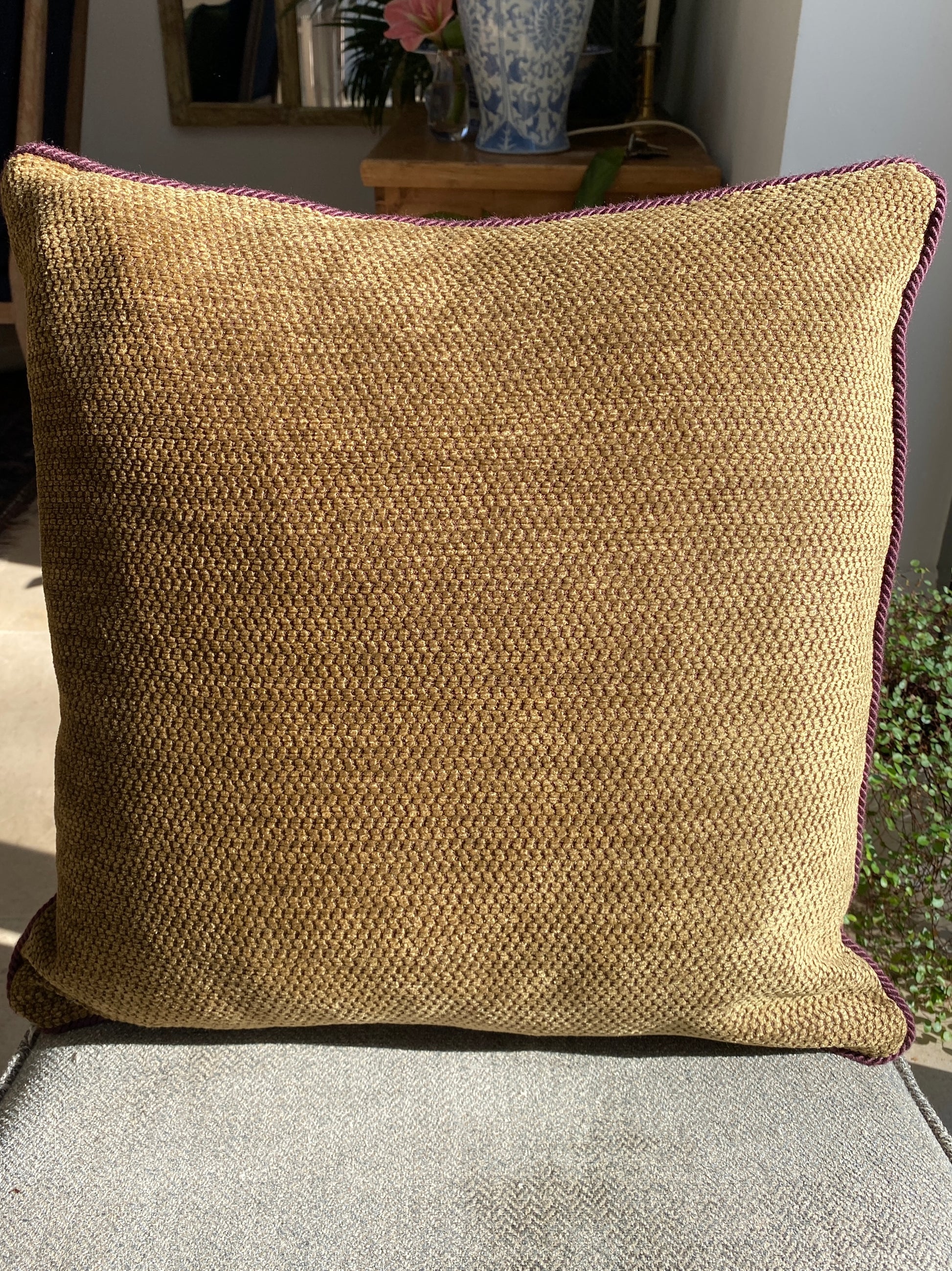 Textured burnished gold chenille cushion on a chair with a blurred background