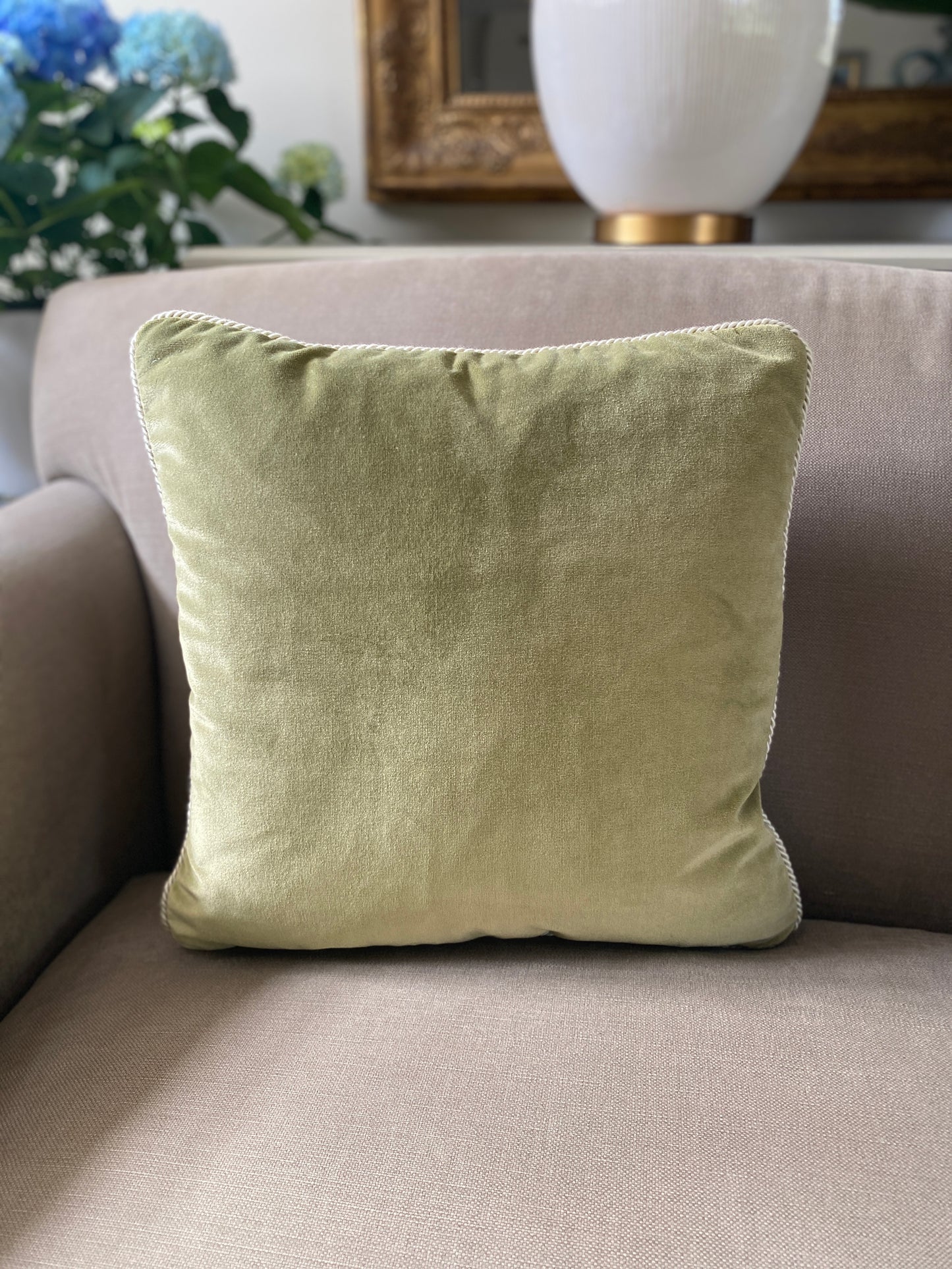 Moss green velvet square cushion with natural toned cord trim. Measures 43 43cm.
