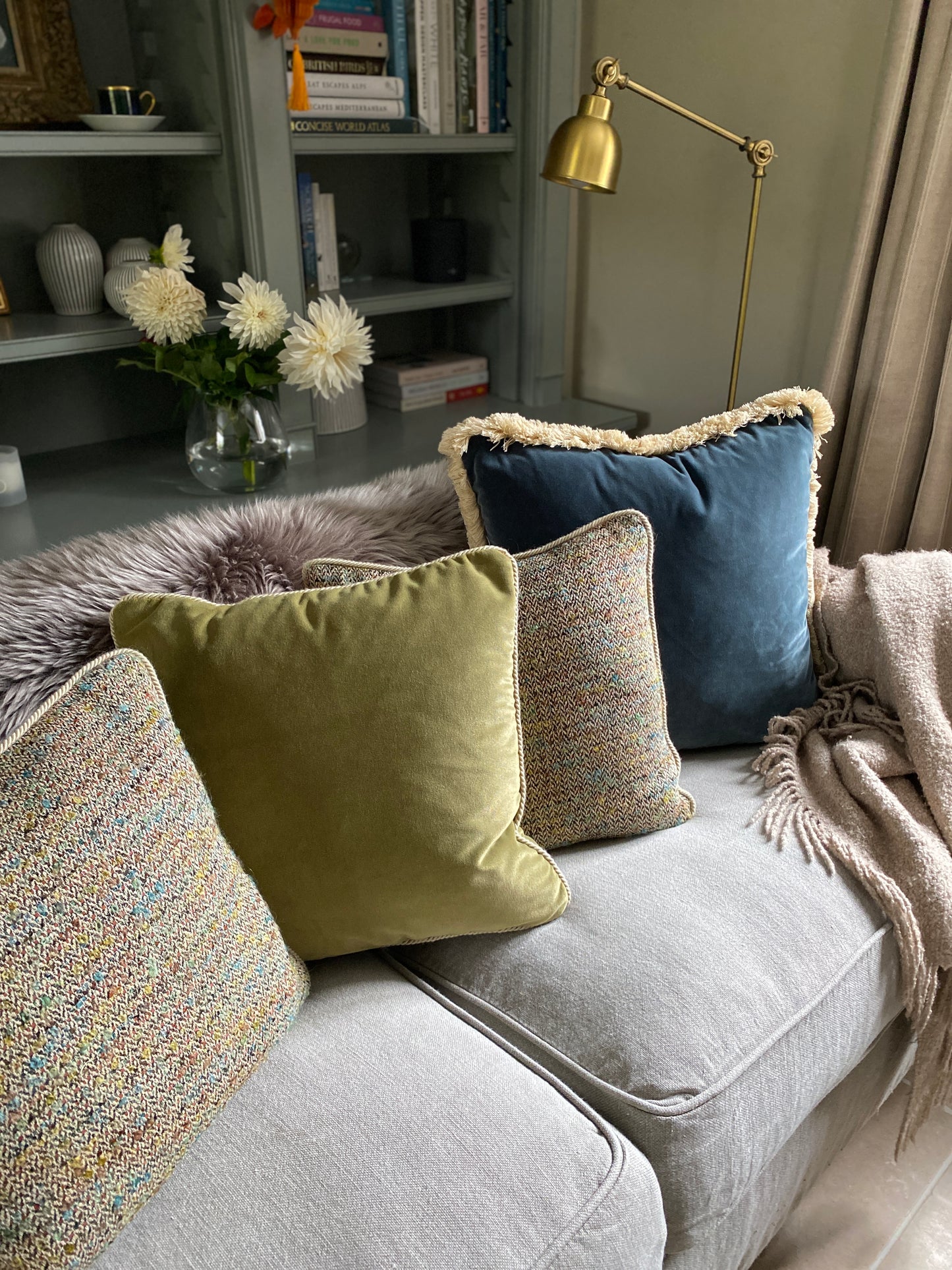 Woven cushions sitting with a teal velvet cushion and a moss green velvet cushion.