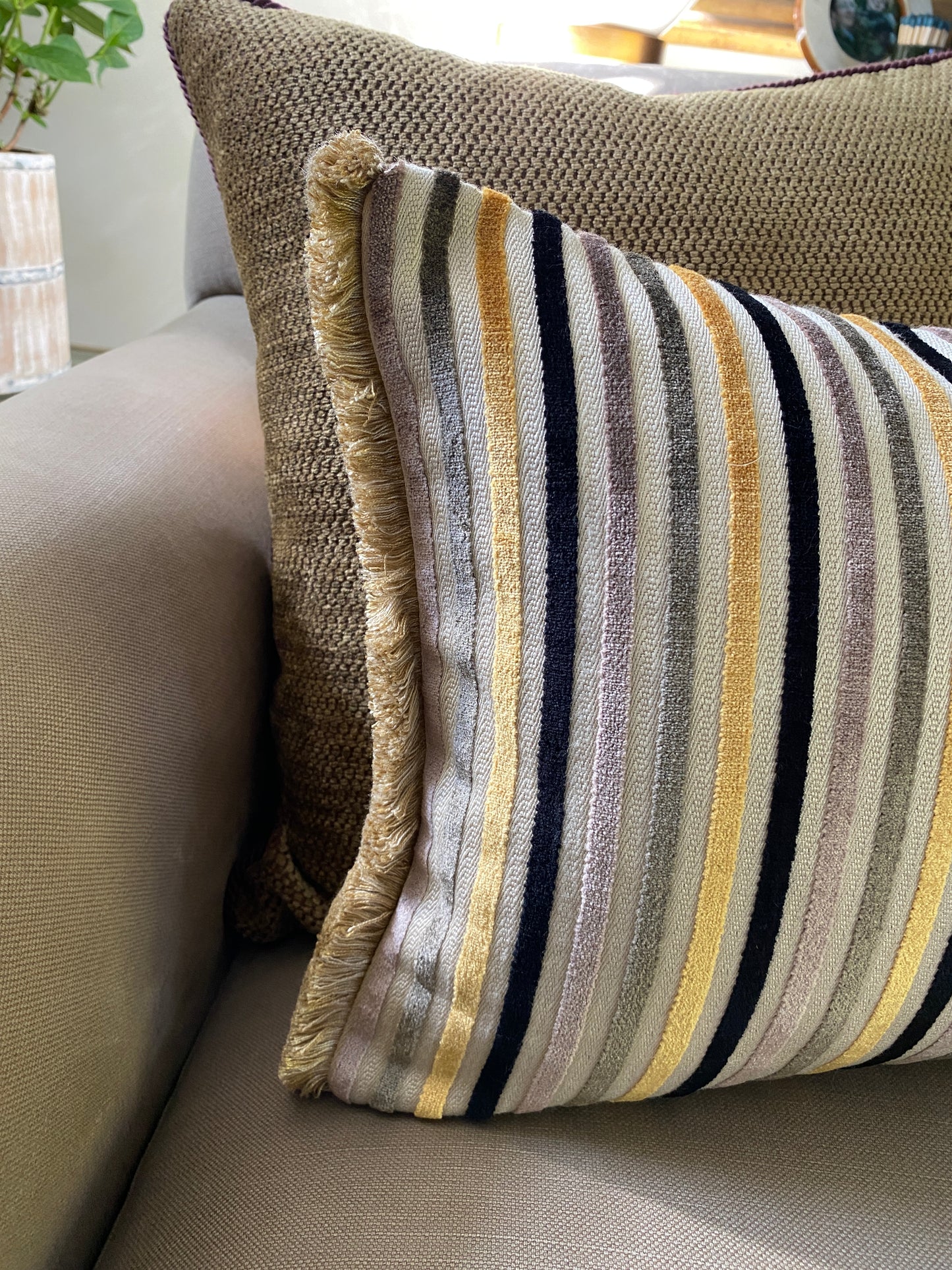Close up to show the fringing on either end of the striped cushion