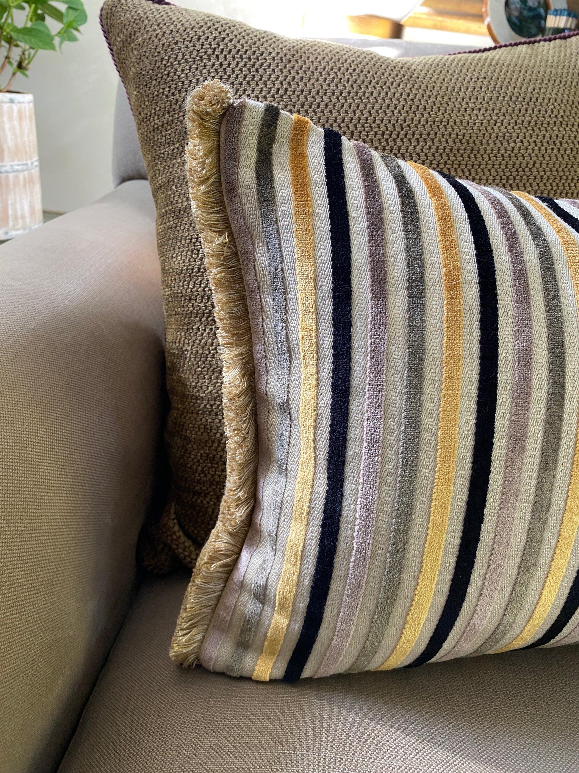 Close up to show the fringing on either end of the striped cushion