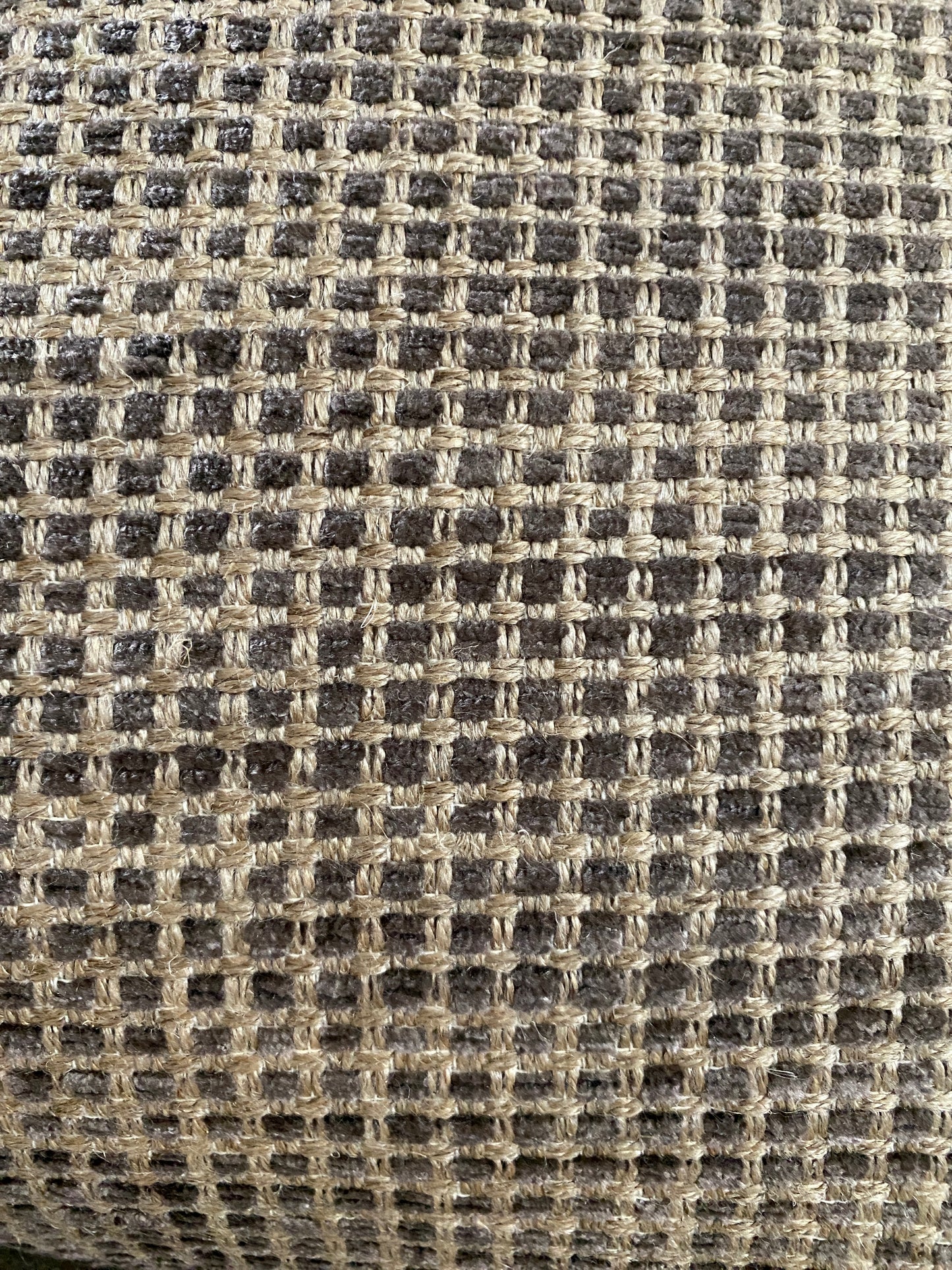 Close up of cushion chenille fabric in shades of brown with sand background.