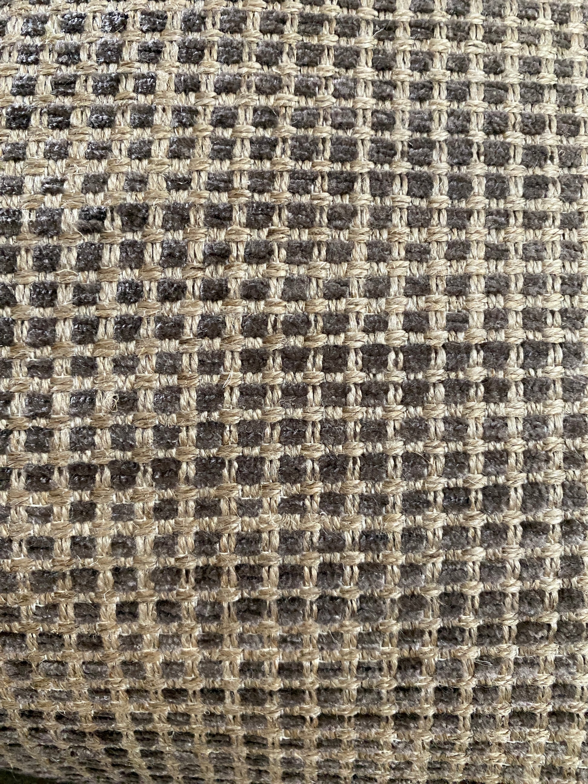 Close up of cushion chenille fabric in shades of brown with sand background.