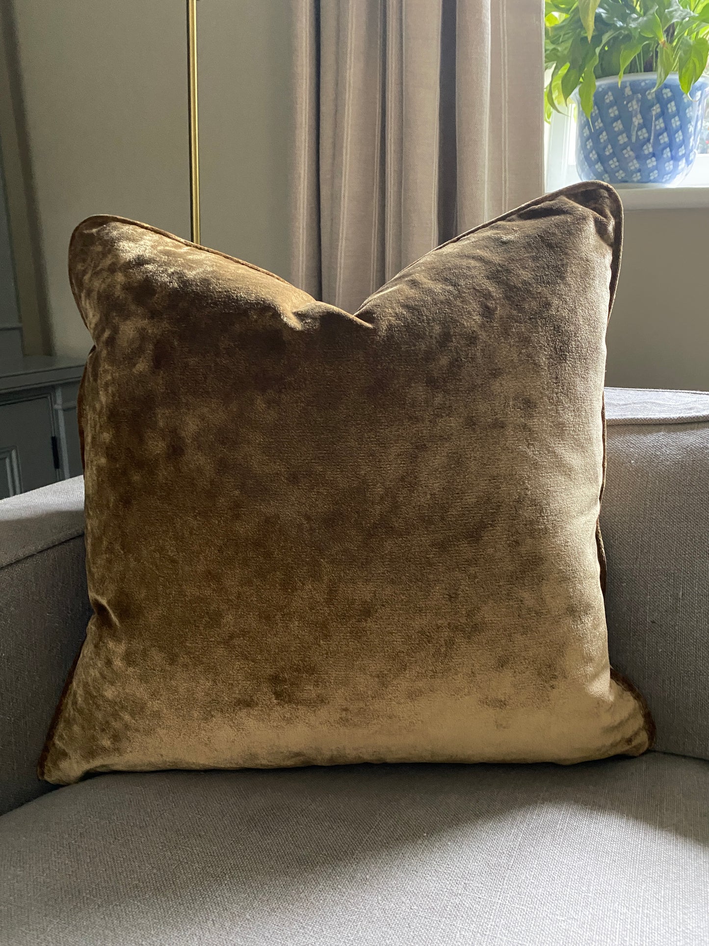 Antique gold velvet square cushion on a sofa.