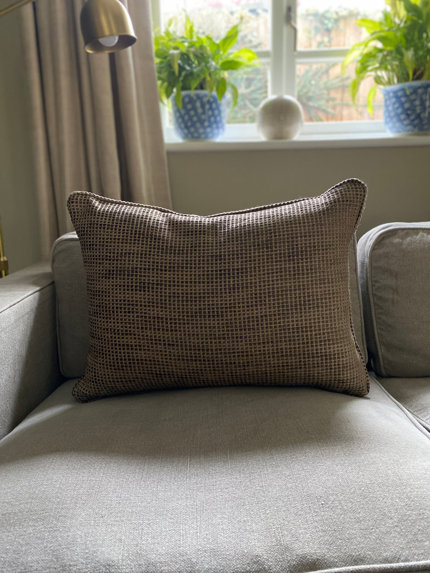 Earthy brown textured chenille rectangular cushion on a sofa.