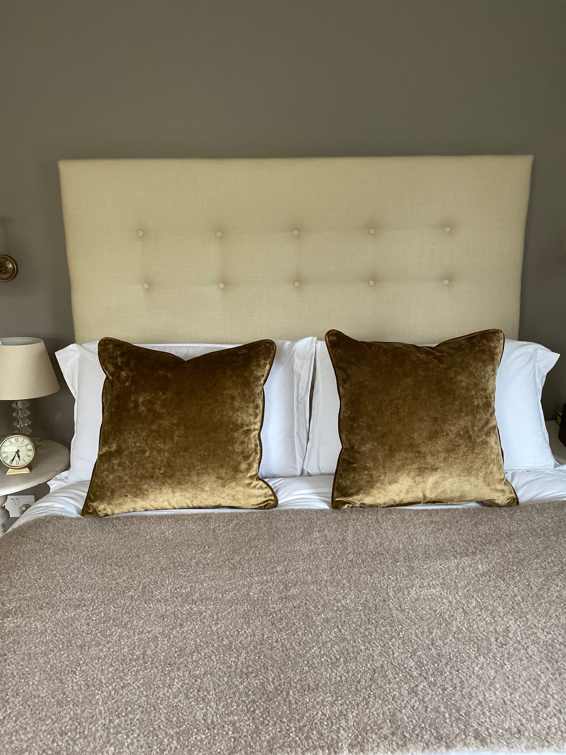Two antique gold velvet cushions on a bed.