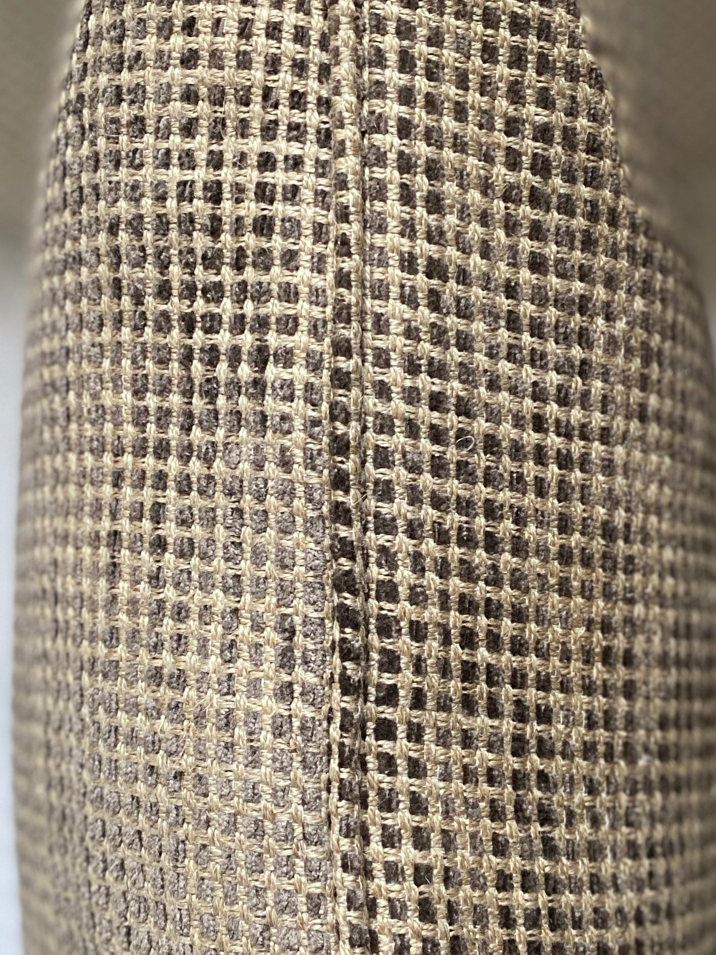 Close up of the cushion fabric showing a self piped edging in shades of brown with a sand background.