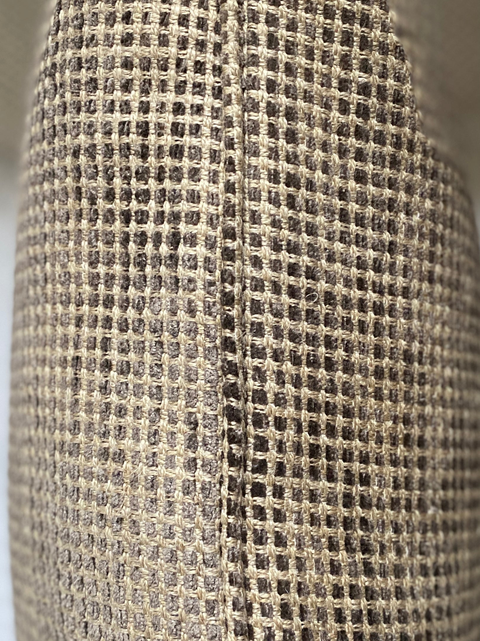 Close up of the cushion fabric showing a self piped edging in shades of brown with a sand background.