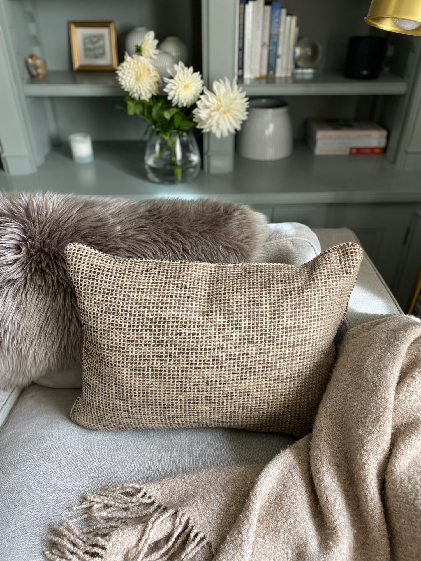 Textured earth browns chenille cushion on a sofa with a throw.