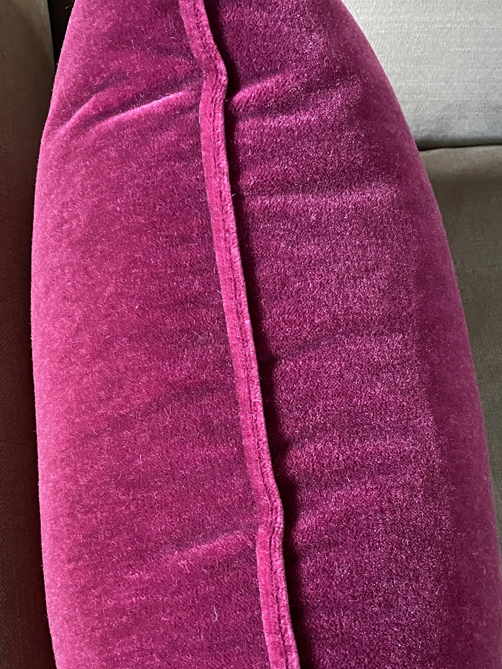 raspberry mohair velvet cushion on its edge showing the self piping trim