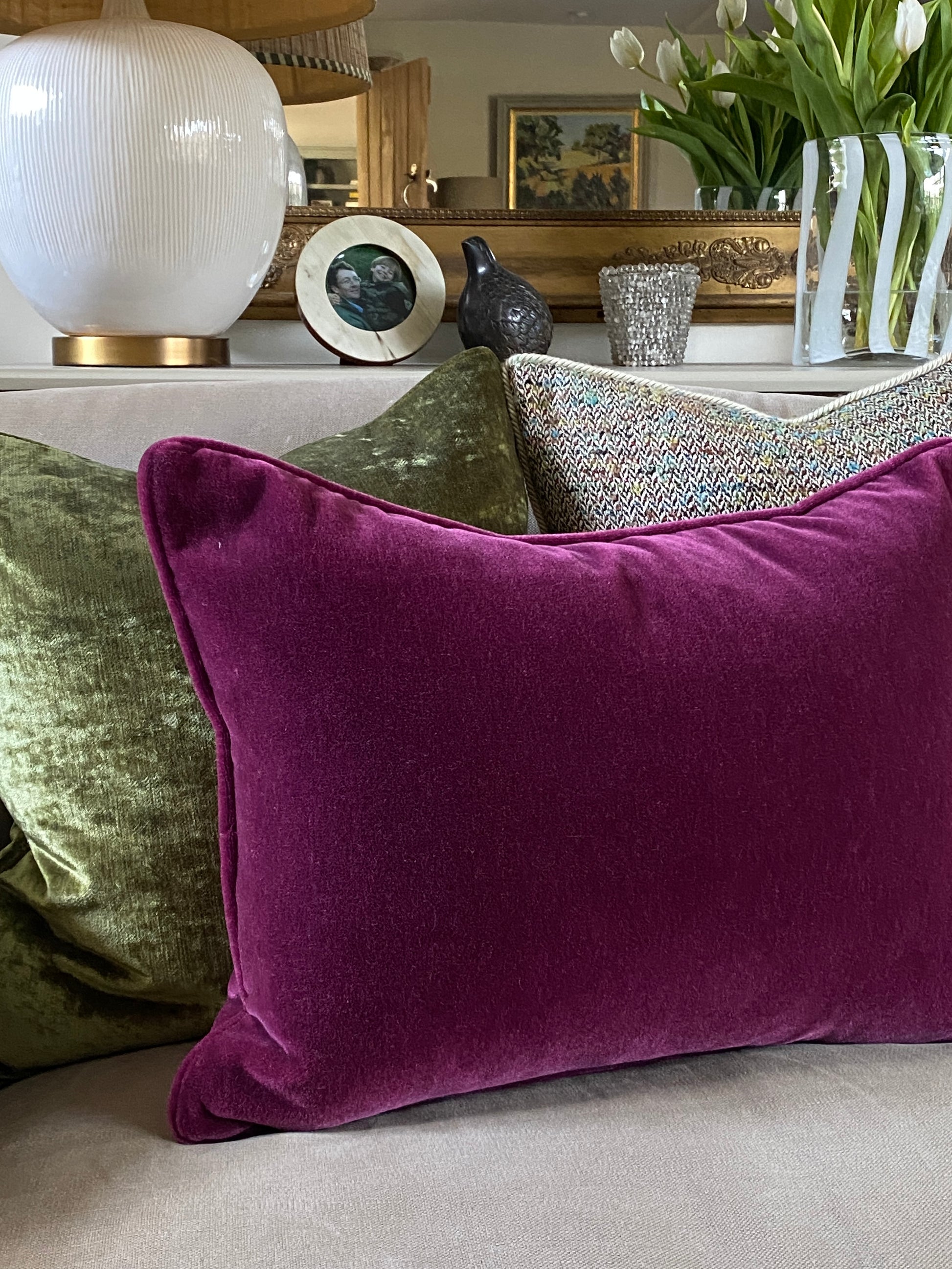 Raspberry mohair velvet  cushion on a sofa with green cushions in the behind